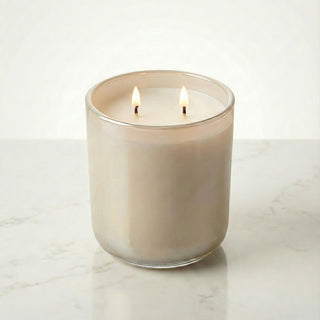 Beachside Dream – Staycation beach-inspired premium coconut apricot wax candle lit with dual warm flames, luminous iridescent medium beige glass vessel glowing softly