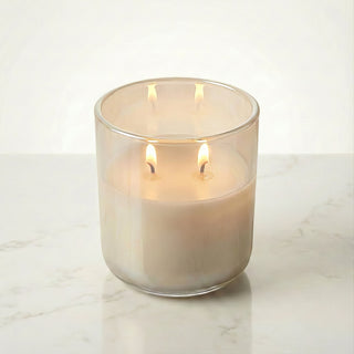 Beachside Dream – Staycation beach-inspired premium coconut apricot wax candle lit with dual warm flames, luminous iridescent medium beige glass vessel glowing softly