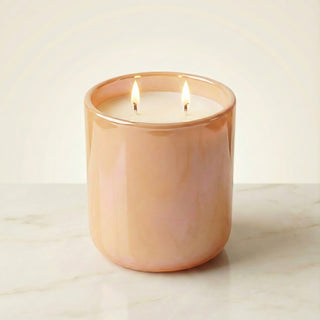 Sun-Kissed Glow – Staycation sunset-inspired premium coconut apricot wax candle lit with dual warm flames, radiant iridescent peach glass vessel glowing softly