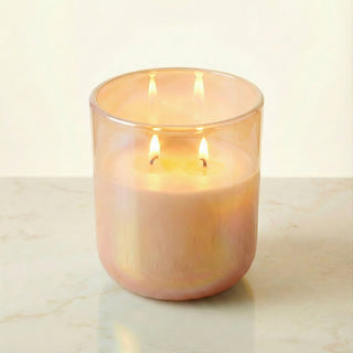 Sun-Kissed Glow – Staycation sunset-inspired premium coconut apricot wax candle lit with dual warm flames, radiant iridescent peach glass vessel glowing softly