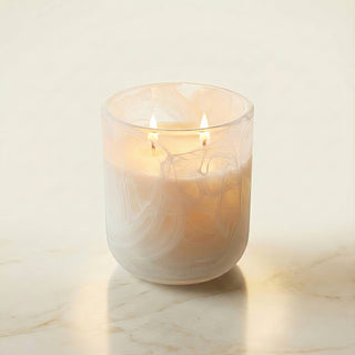 Glory Strength Light Shadow 2-wick luxury candle with low flames burning inside a frosted opalescent white marbled glass vessel, close-up product shot on marble