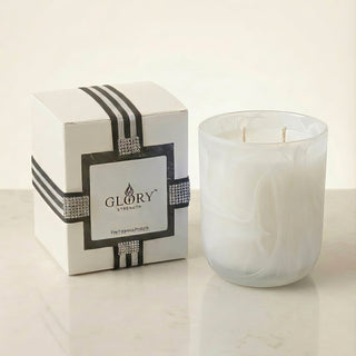 Glory Strength Light Shadow 2-wick luxury candle in a white pearl marbled glass vessel beside its signature gift box with black stripe ribbon and rhinestone detail