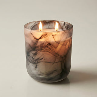 Glory Strength Shadow Light 2-wick luxury candle lit and glowing warm amber light through a black marbled glass vessel, Yin and Yang Collection