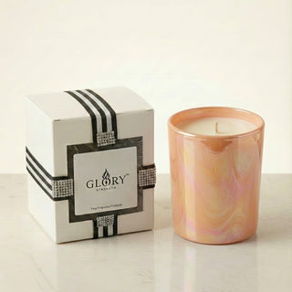 Glory Strength Sun-Kissed Glow 8oz luxury scented candle in an iridescent peach glass vessel, displayed beside a white and black striped gift box with rhinestone ribbon detail on a marble surface.