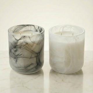 Glory Strength Yin and Yang Collection: Shadow Light in a black and white marbled glass vessel beside Light Shadow in a white pearl marbled glass vessel, both 2-wick luxury candles unlit on a marble surface